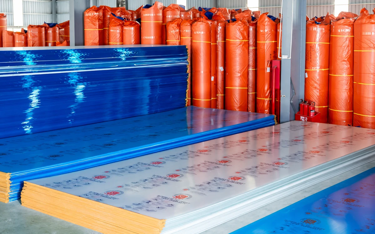 Tấm Polycarbonate phủ màng bảo vệ SL xếp phẳng và các cuộn hàng đóng gói trong kho.